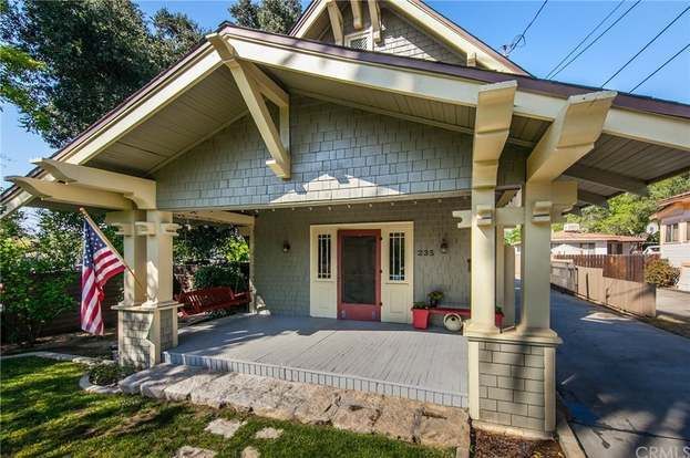 A house with a porch and an american flag in front of it.