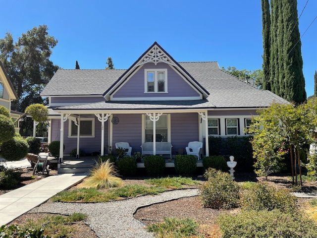 A purple house with a white porch and a gray roof