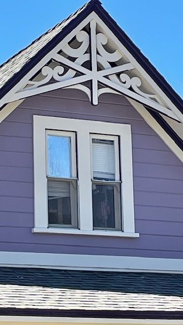 A purple house with white trim and a window