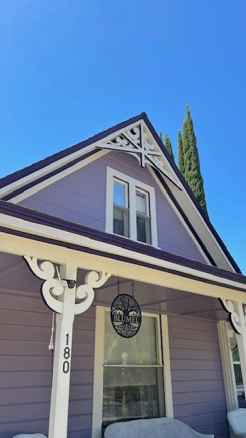 A purple house with a porch and a blue sky in the background