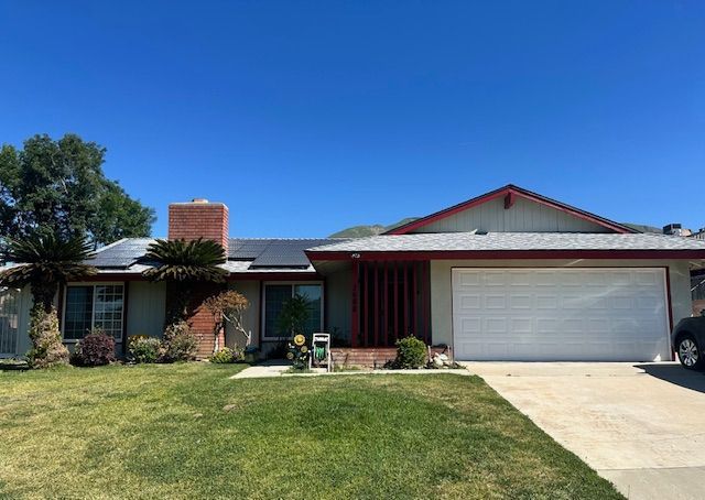 A house with solar panels on the roof and a car parked in front of it.