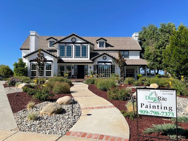 A large white house with a painting sign in front of it.