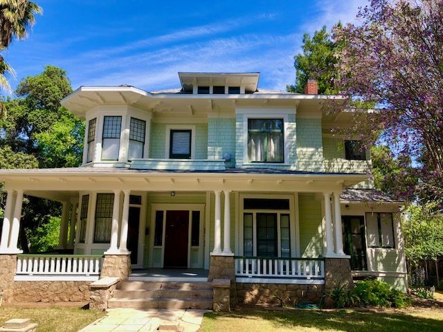 A green and white house with a large porch