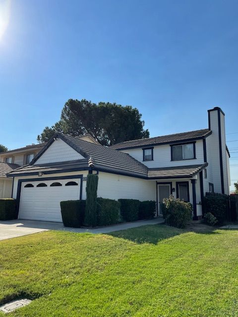 A white house with a brown roof and a white garage door