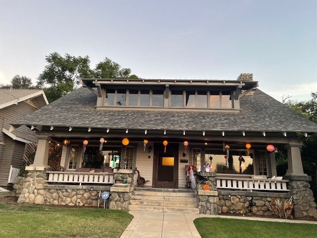 A large house with a gray roof and a stone porch