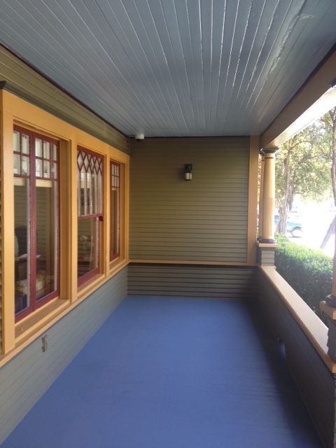 A porch with a blue floor and lots of windows