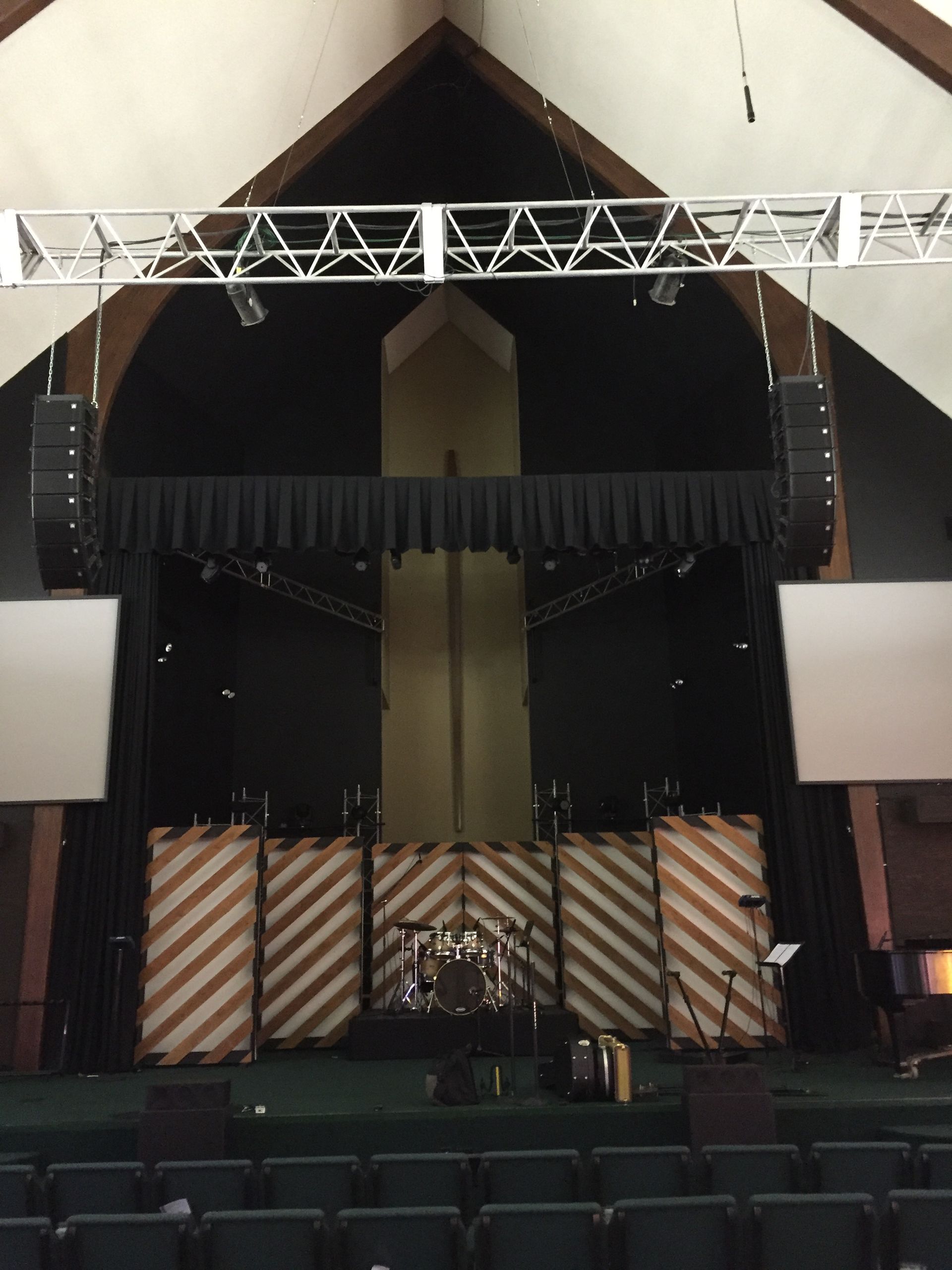 An empty auditorium with a stage and a cross in the background