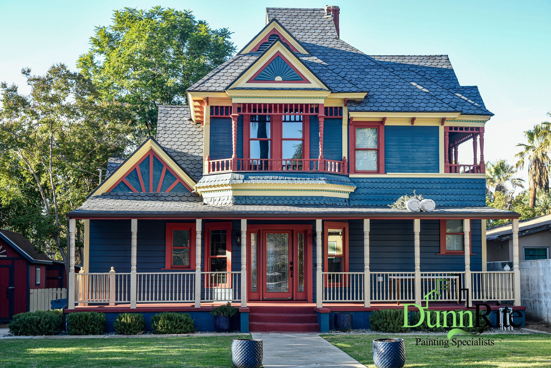Victorian-style house with dark blue exterior, red trim, and wraparound porch in Near Redlands, CA.