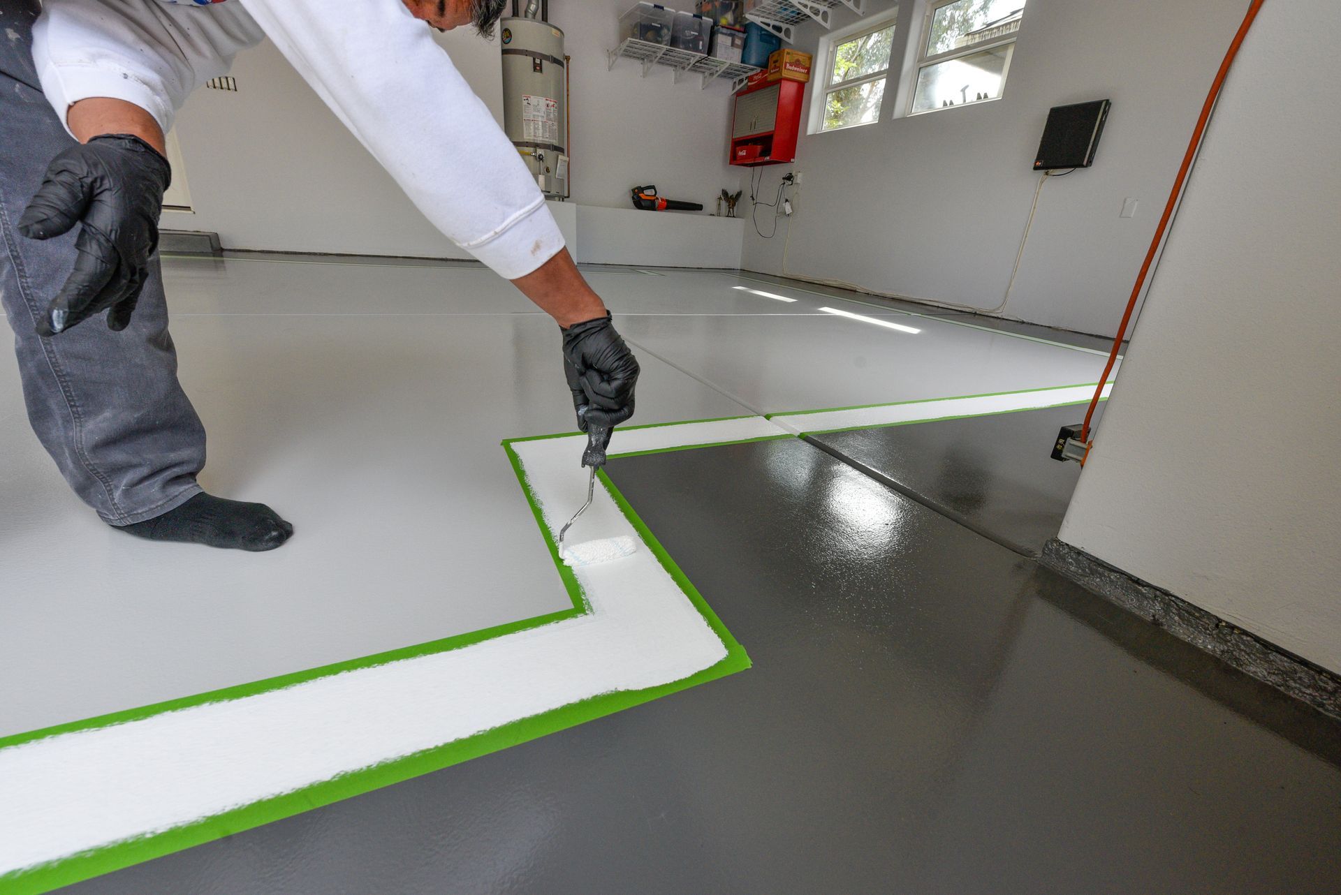A person is painting epoxy on floor in a garage in Redlands.