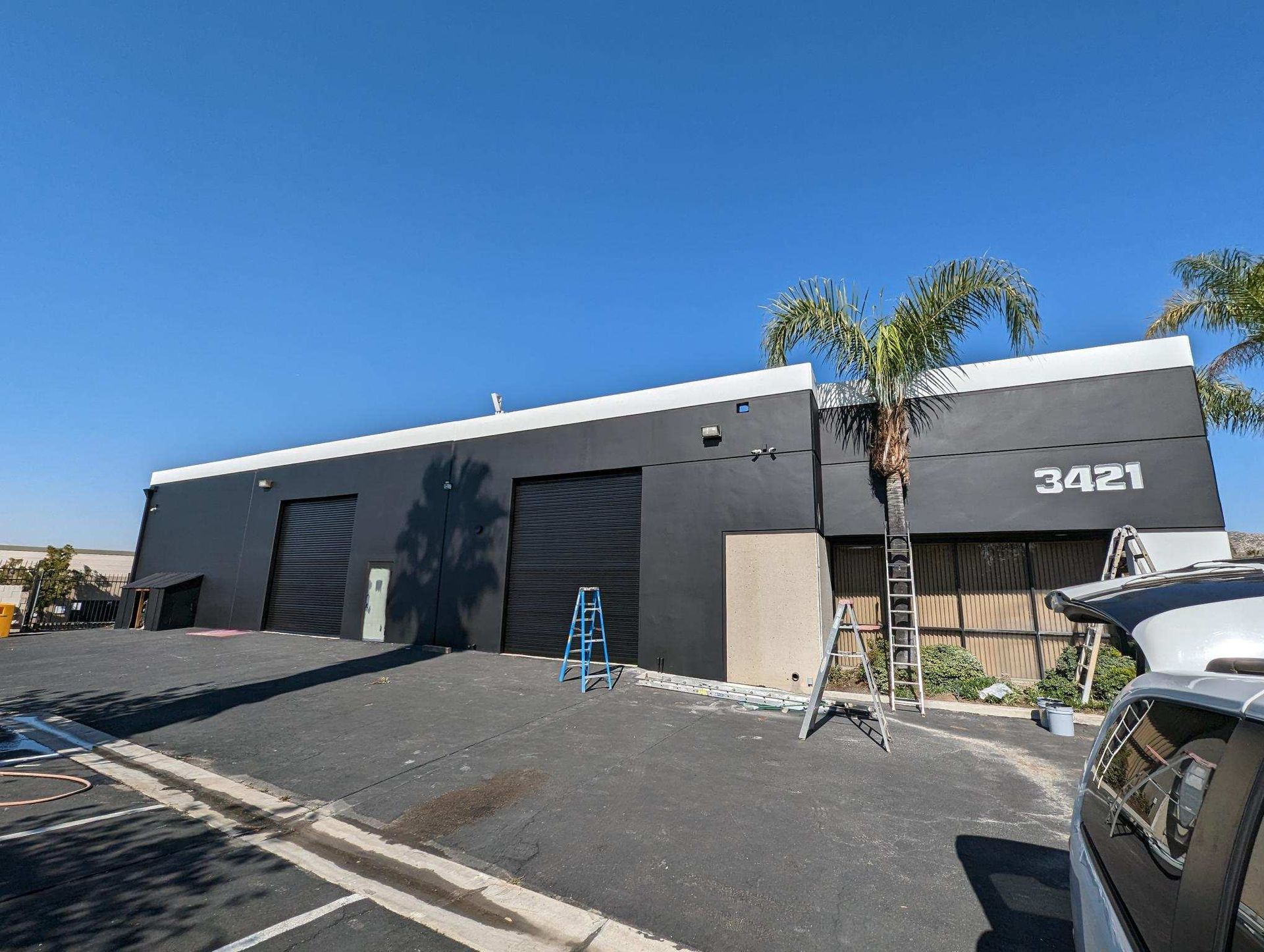 A car is parked in front of a large black building.