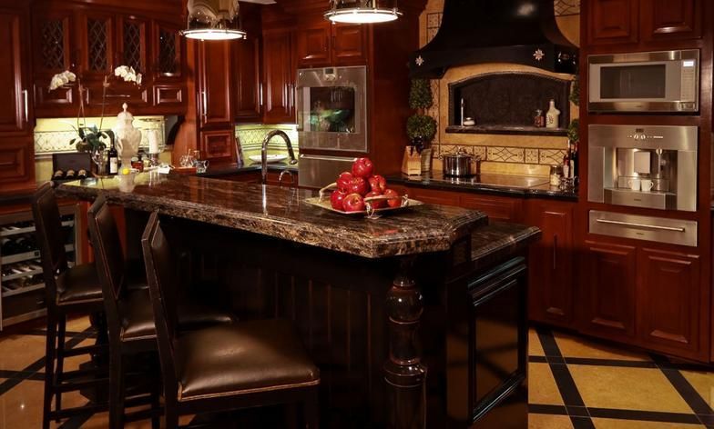 A kitchen with a large island and a bowl of apples on the counter.