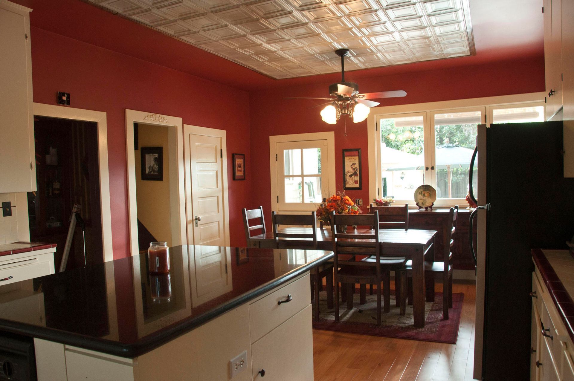 A kitchen painted red with a table and chairs and a ceiling fan in Redlands, CA