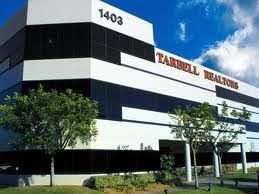 A freshly painted large white and black building with trees in front of it.