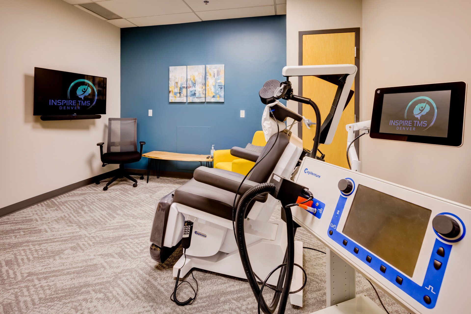 TMS treatment chair in a room with television and additional seating.
