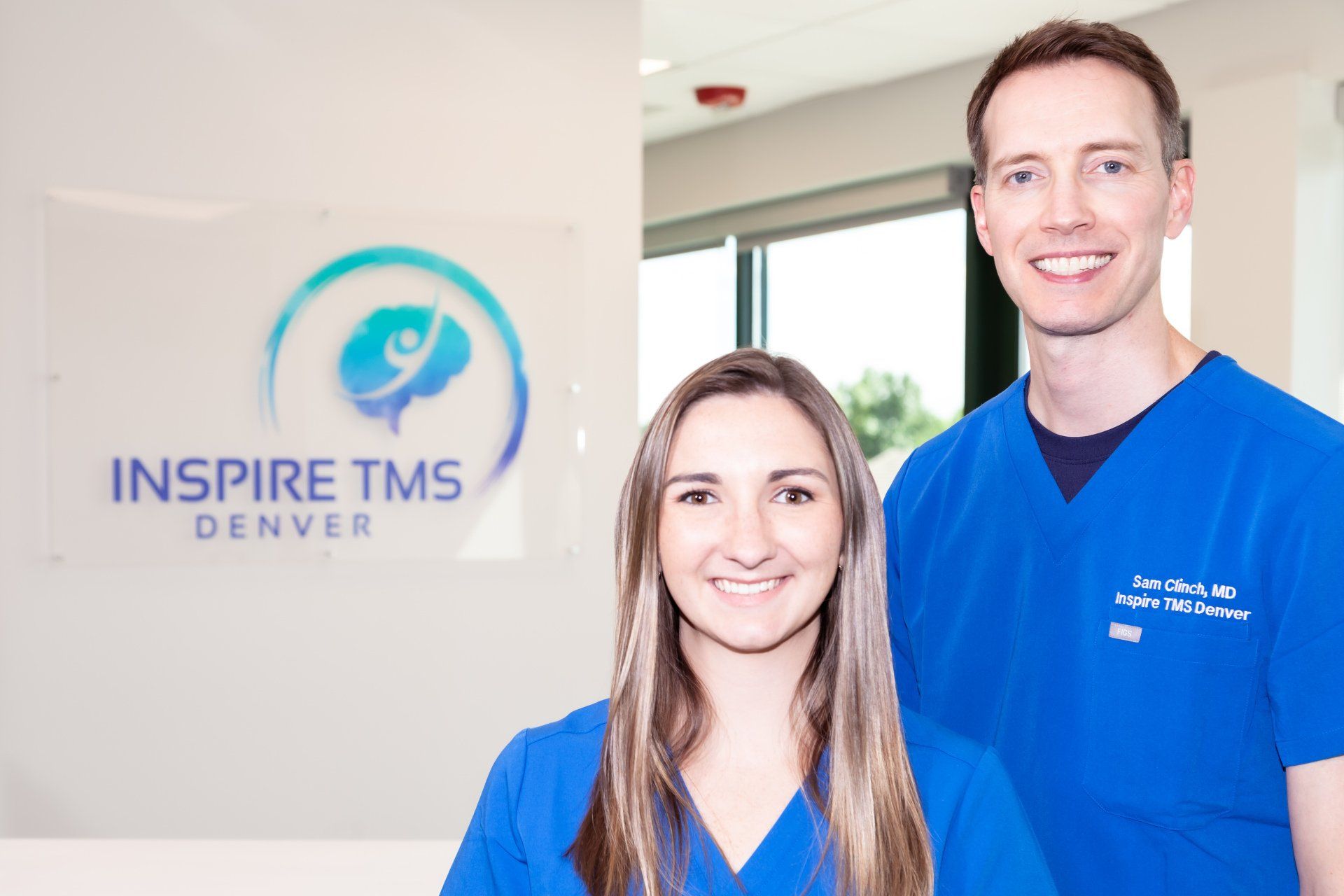 a man and a woman standing in front of a sign that says inspire tms denver