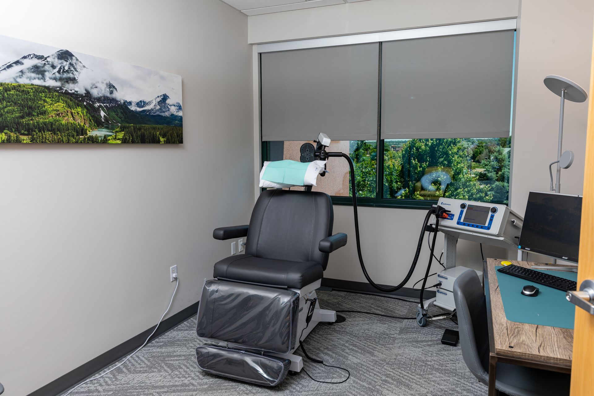 A doctor 's office with a chair , desk and computer.