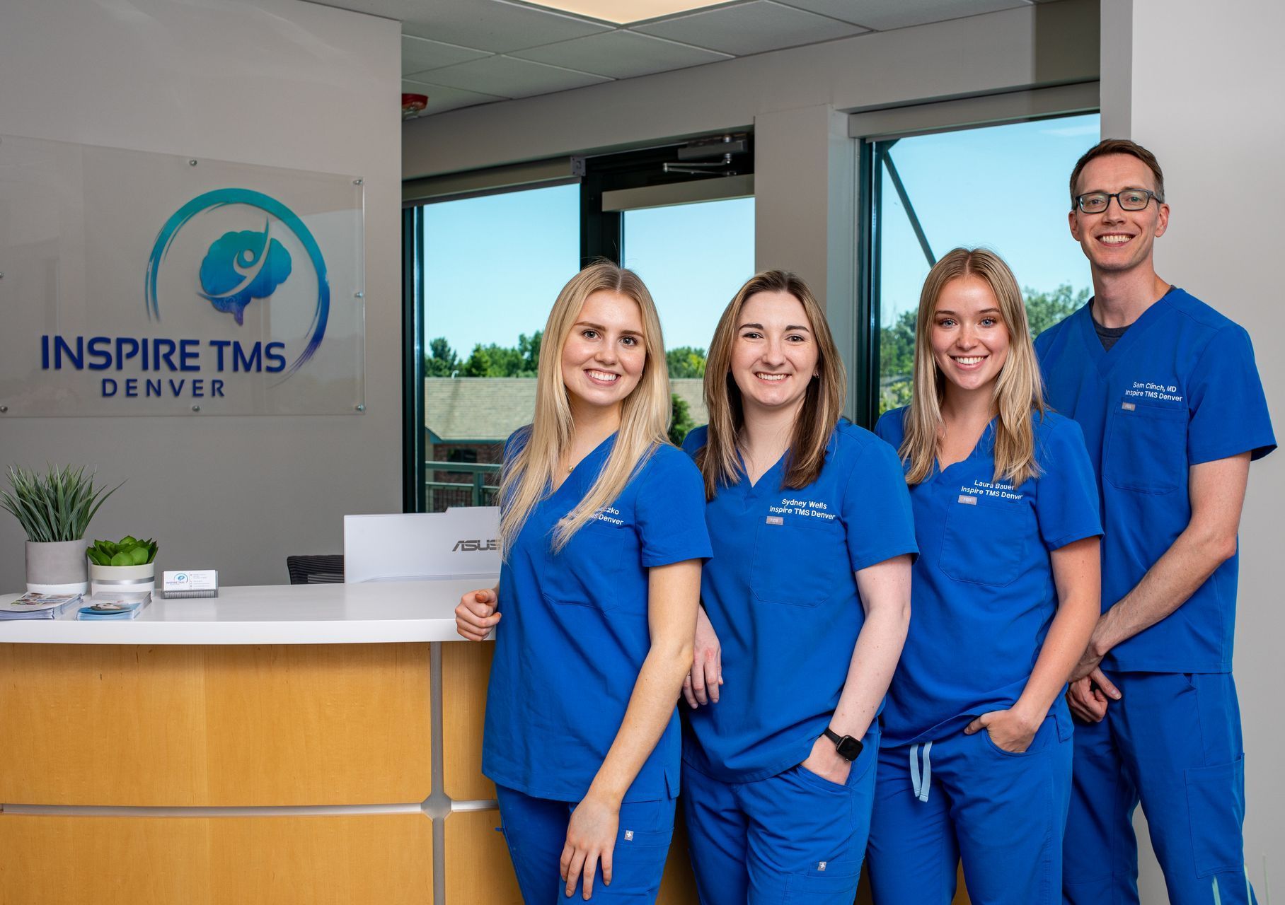 a group of people in blue scrubs are standing in front of a counter .