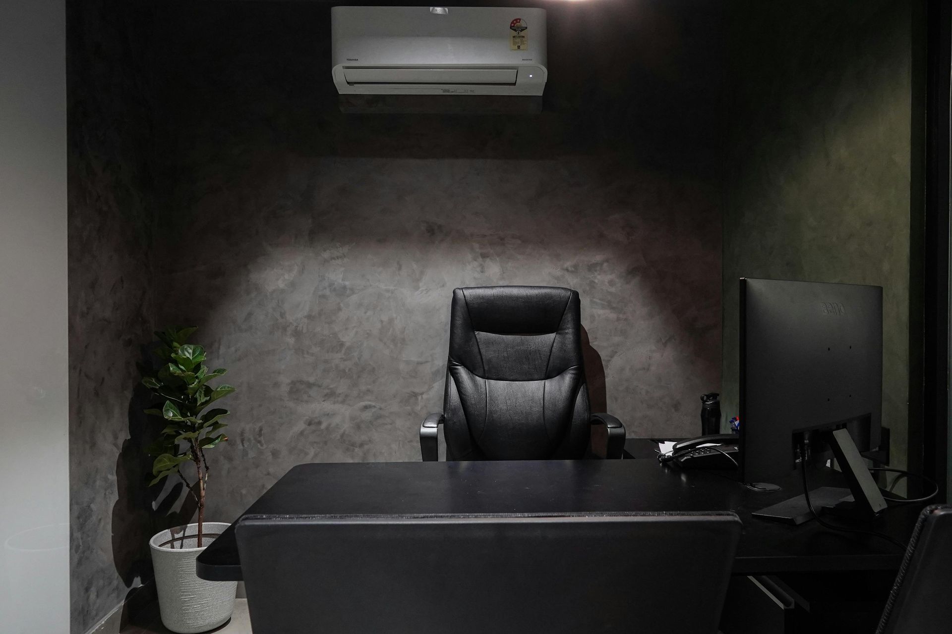 A black office chair is sitting at a desk in a dark room.