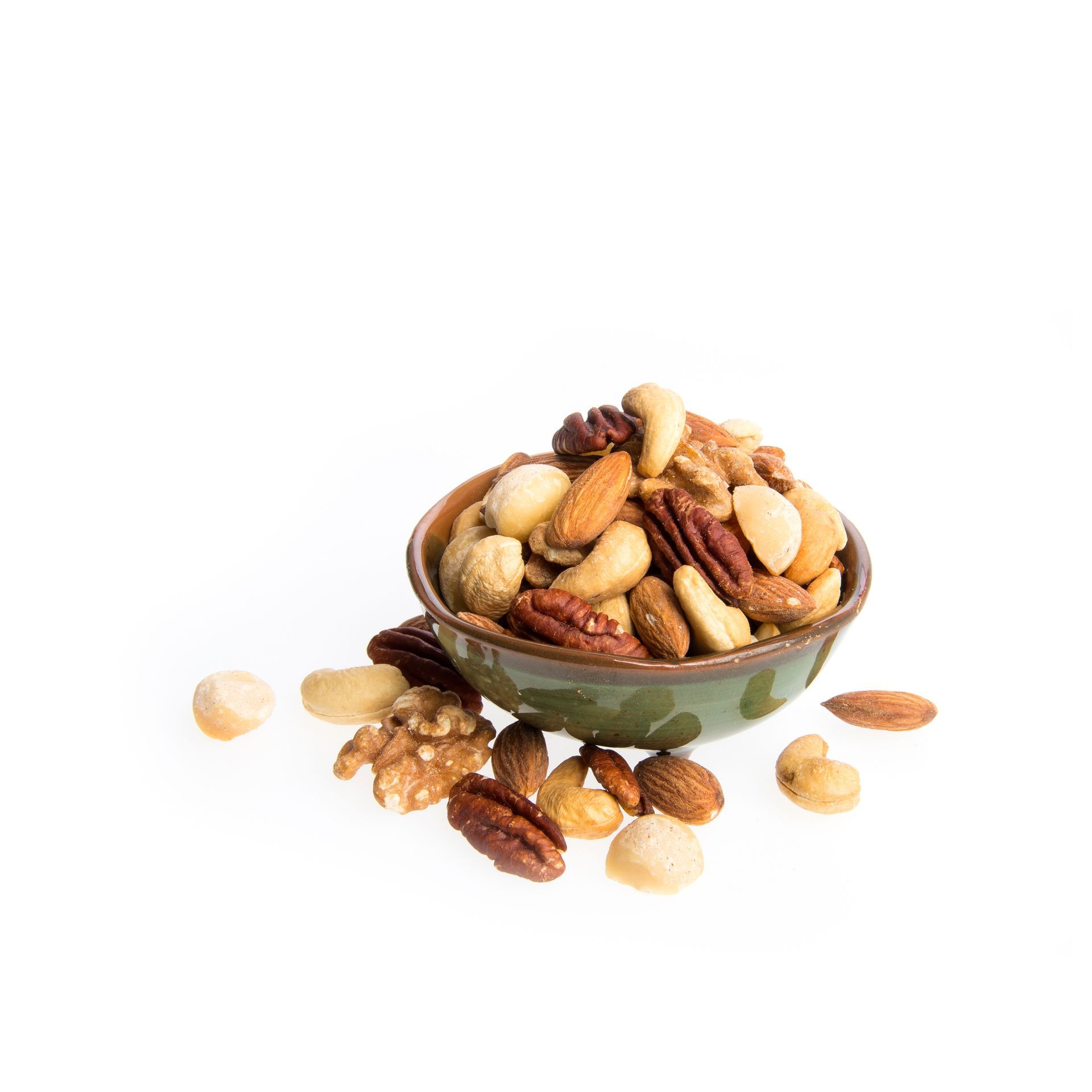 Cuenco de frutos secos mixtos sobre una superficie blanca, que incluye almendras, nueces pecanas, anacardos y nueces.