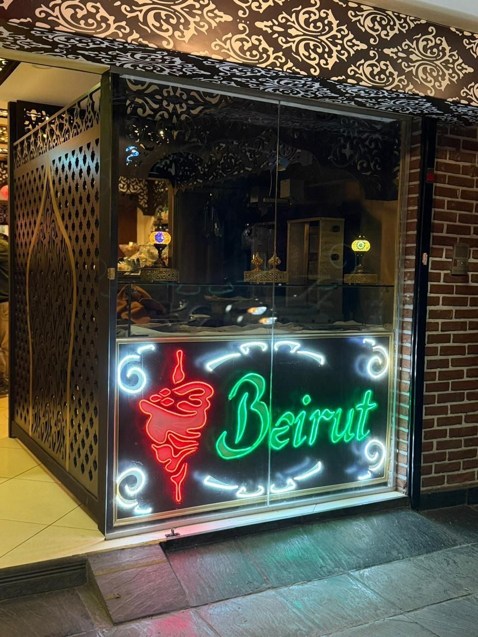 Letrero de neón de un restaurante de Beirut con un icono de narguile rojo y letras verdes en la fachada .