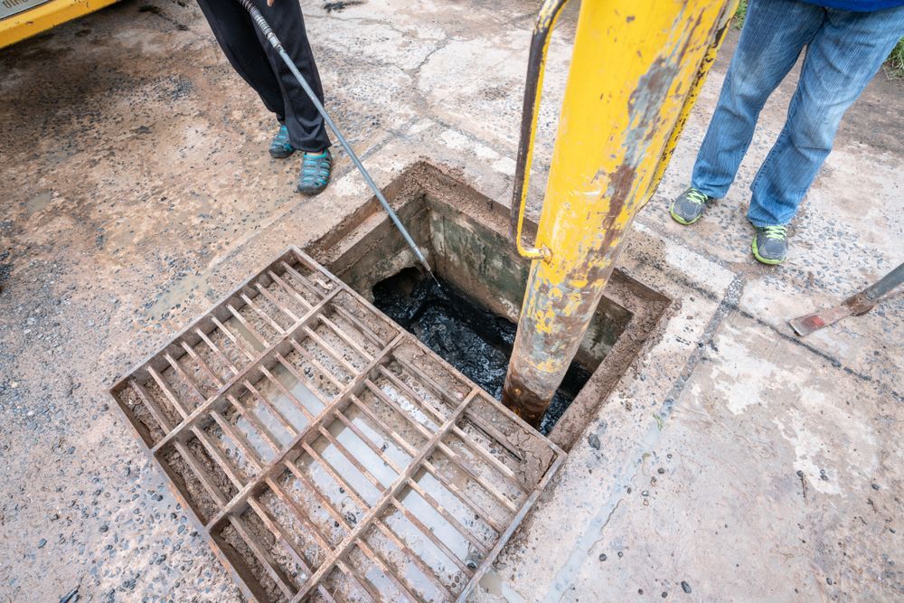 Open Sewer Drain With Yellow Equipment Inside — Raptor Waste Management In Nerang, QLD
