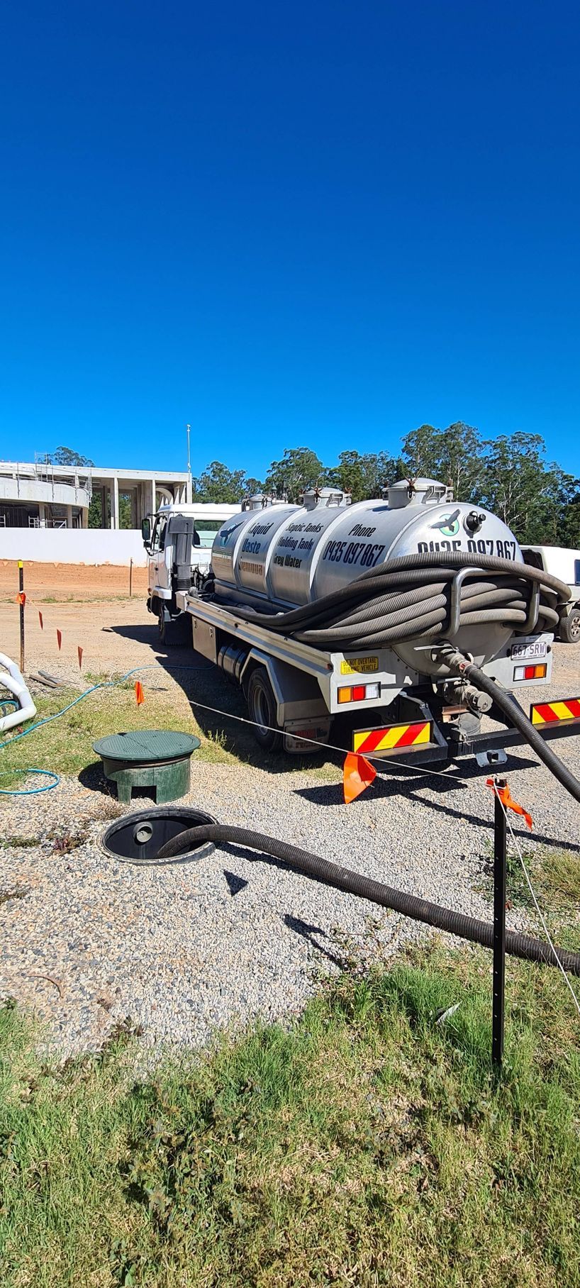 Septic tank truck, on a gravel lot next to some grass, with a clear blue sky in the background — Raptor Waste Management in Coolangatta, QLD