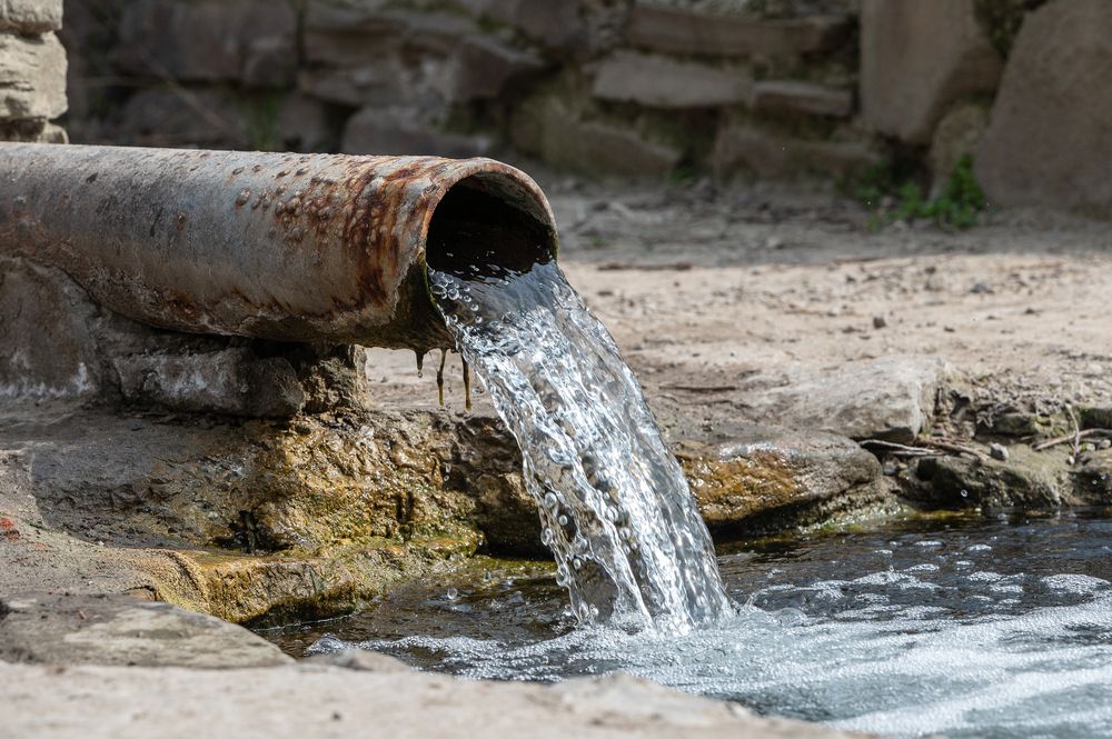 Water Flows From a Rusty Pipe Into a Stone Basin — Raptor Waste Management In Carrara, QLD