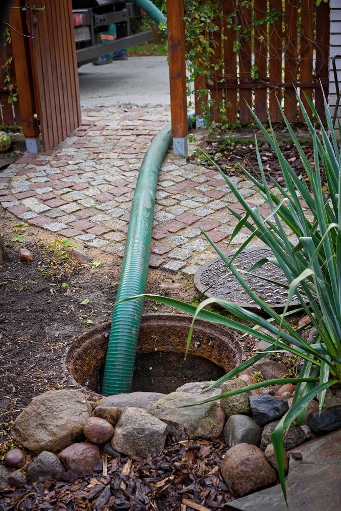 Green Hose Entering an Open Sewer Drain — Raptor Waste Management in Coolangatta, QLD