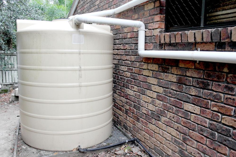 Tan Water Tank Next to a Brick Building — Raptor Waste Management In Uki, NSW