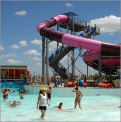 A group of people are playing in a water park with a water slide.