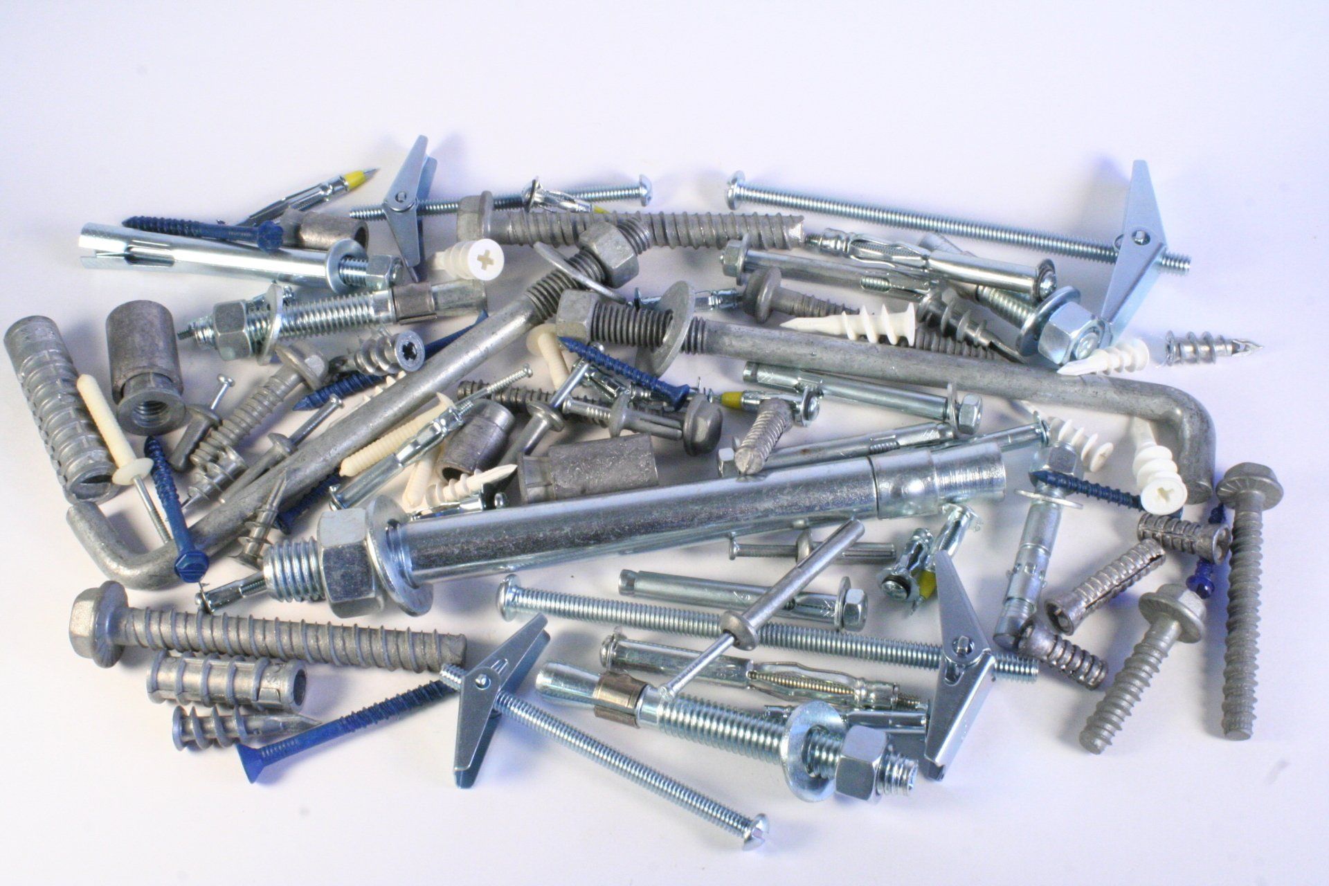 A pile of screws and bolts on a white surface
