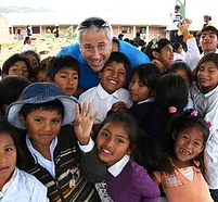 A man is posing for a picture with a group of children.