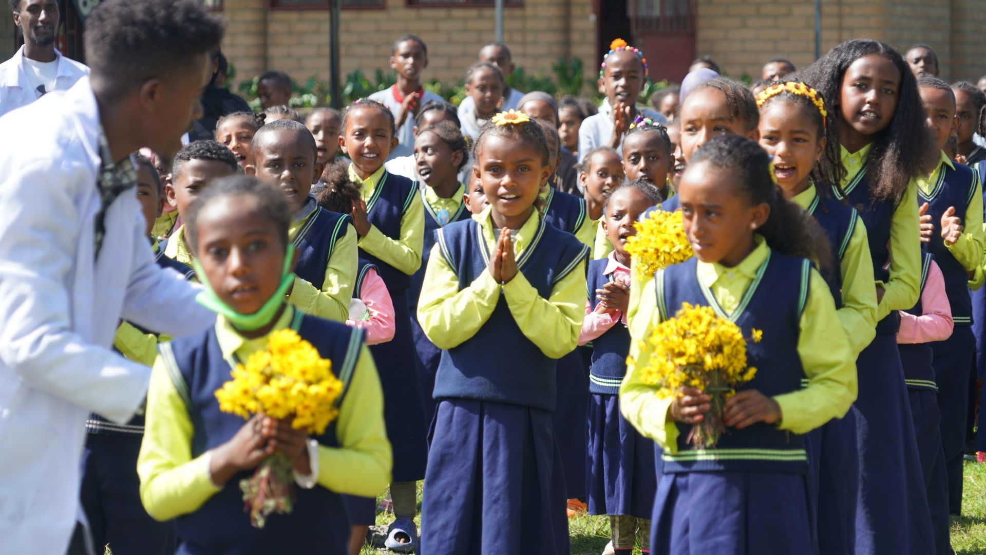 A group of African school children with OSF program holding  yellow flowers.