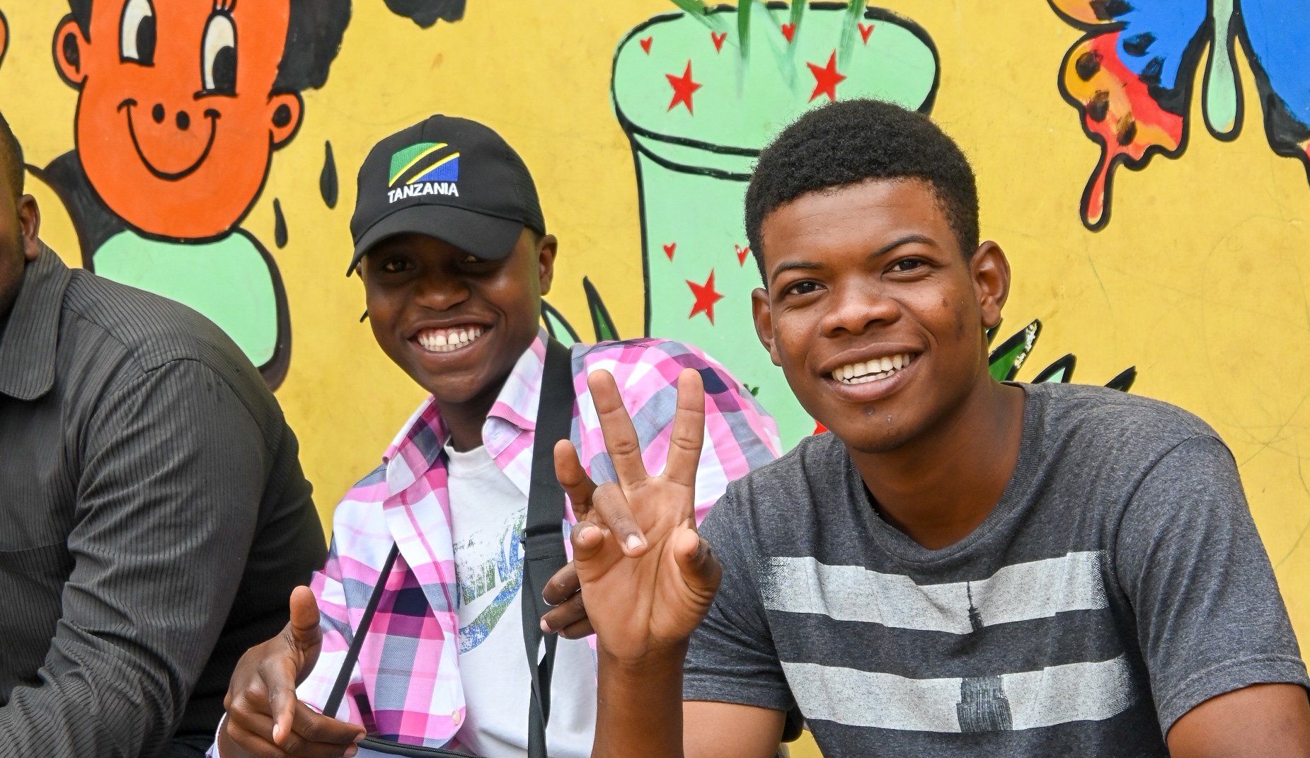 A group of young men are posing for a picture in front of a mural.