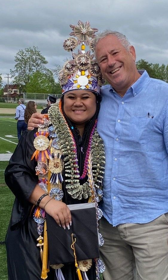 A man is standing next to a woman wearing a graduation cap and gown.