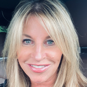 A woman with blonde hair and blue eyes is smiling for the camera.