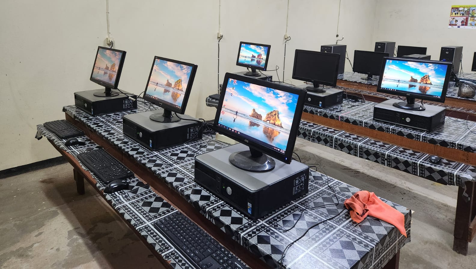 A row of computer monitors are sitting on a table in a computer lab.