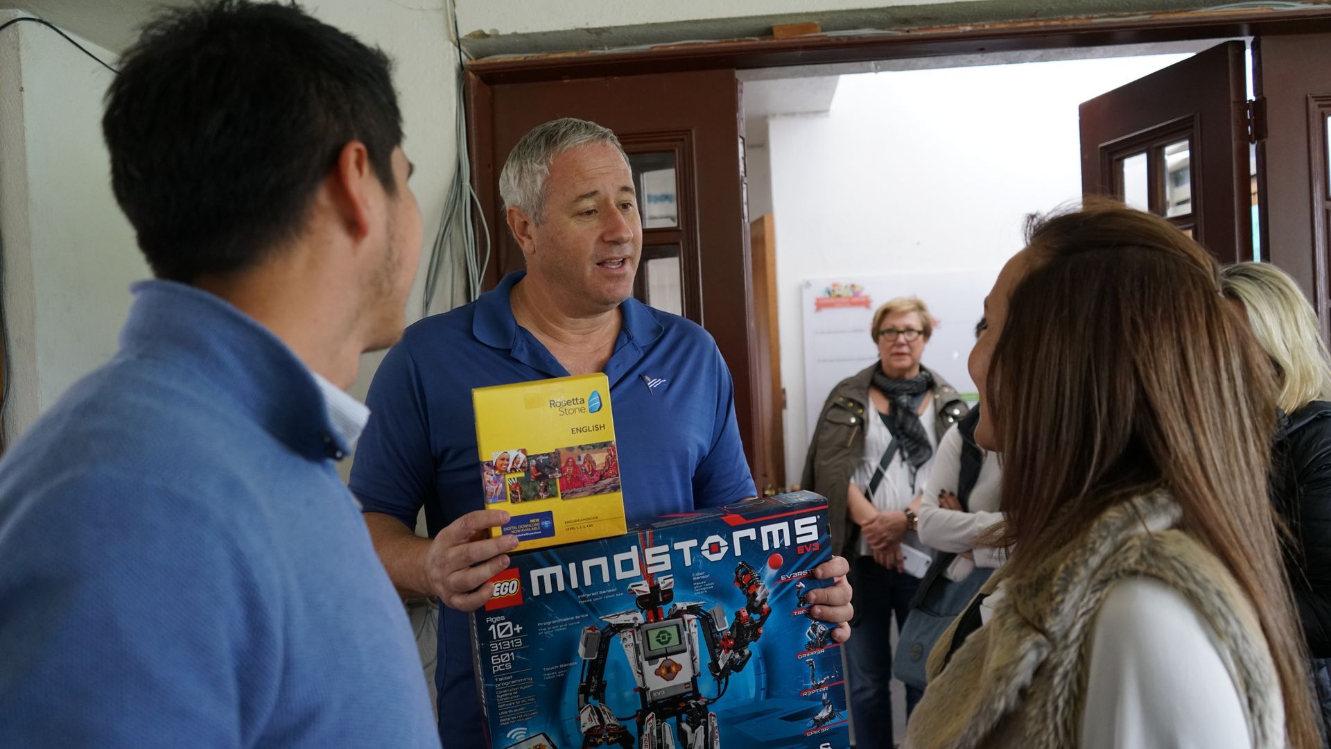 andy stein showing a rosetta stone boxand a LEGO Mindstorms box. Students observing a demo of a small robotic device. orphaned starfish foundation  OSF Robotics Initiative stem education