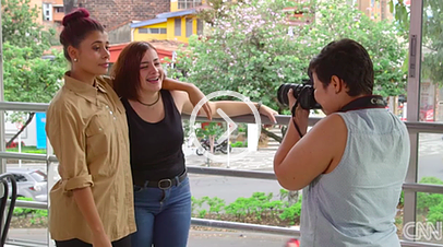 A woman is taking a picture of two women on a balcony.