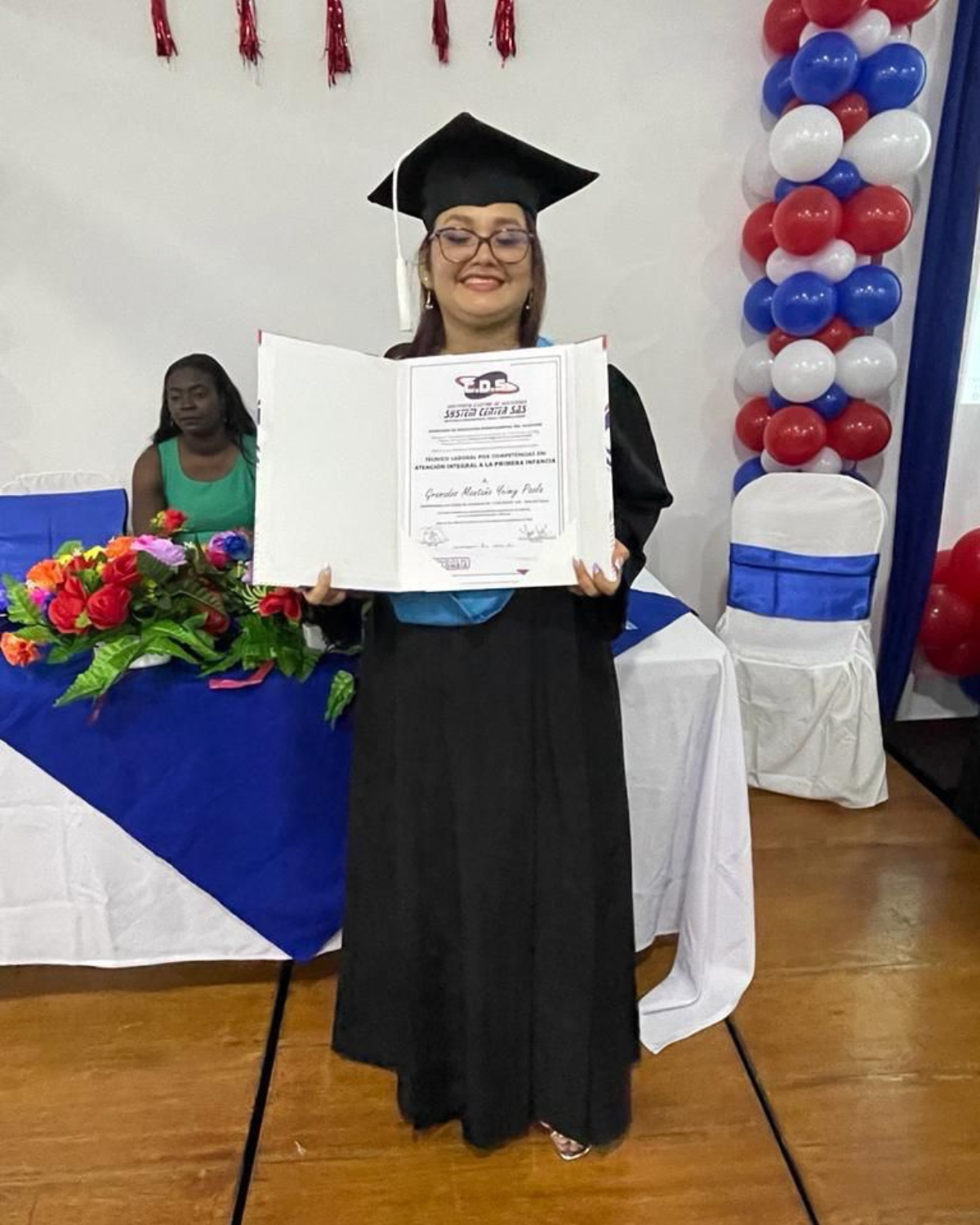 Yeimmy Paola Grenados in a graduation cap and gown is holding a diploma.  osf fundamor colombia andy stein