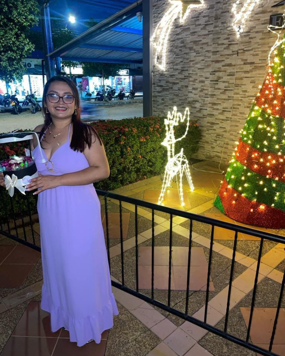 Yeimmy Paola Grenados  in a purple dress is standing in front of a christmas tree. osf fundamor colombia andy stein
