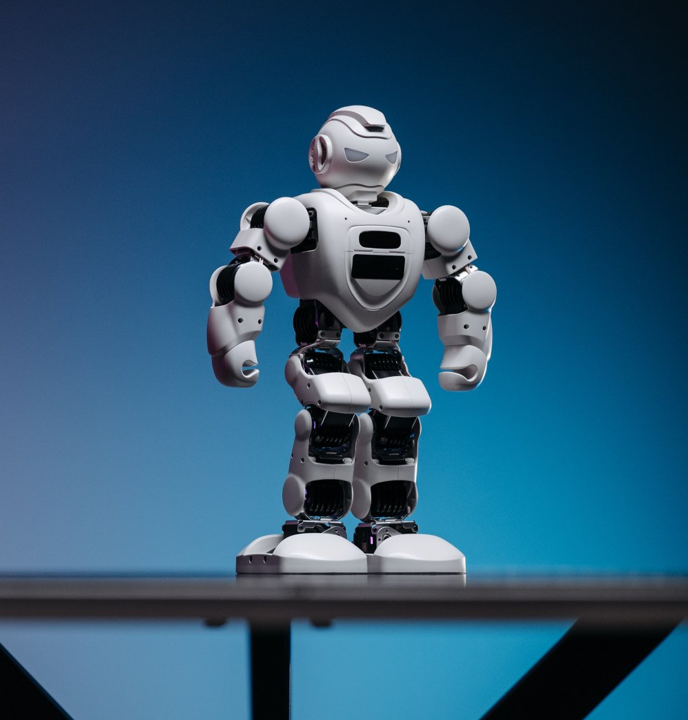A white robot is standing on a table with a blue background