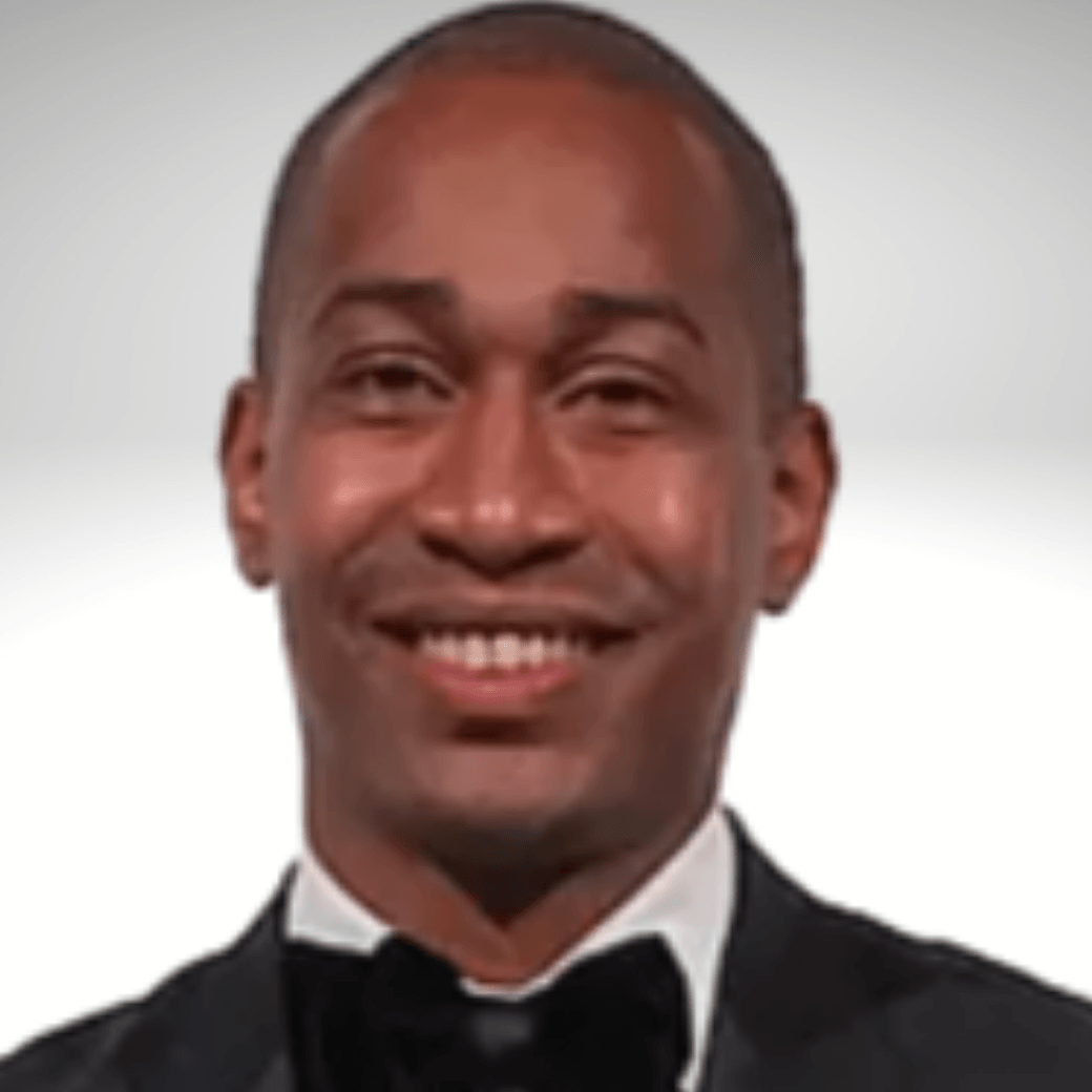 A man in a tuxedo and bow tie smiles for the camera