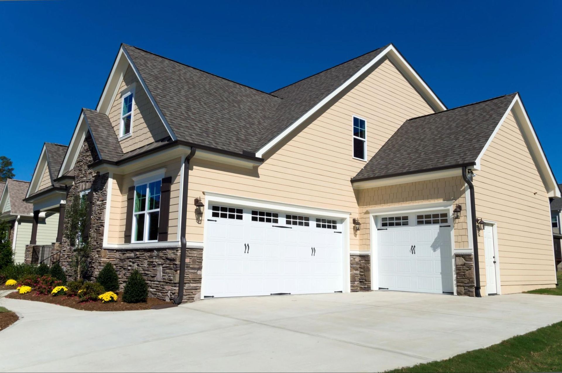 A large house with two garage doors on a sunny day