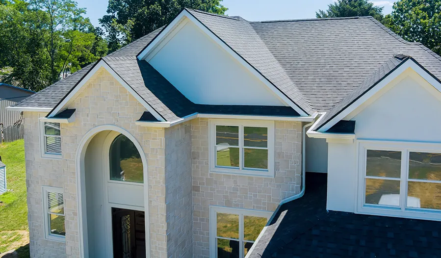 An aerial view of a white house with a black roof.