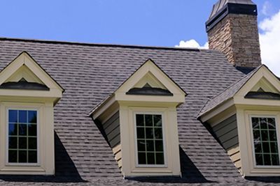 a roof of a house with three windows and a chimney