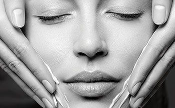 A black and white photo of a woman 's face with her eyes closed.