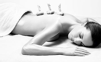 Black and white image of womansreceiving a hot stone treatment on her back
