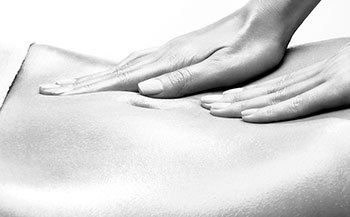 A woman is getting a massage with her hands on her stomach.