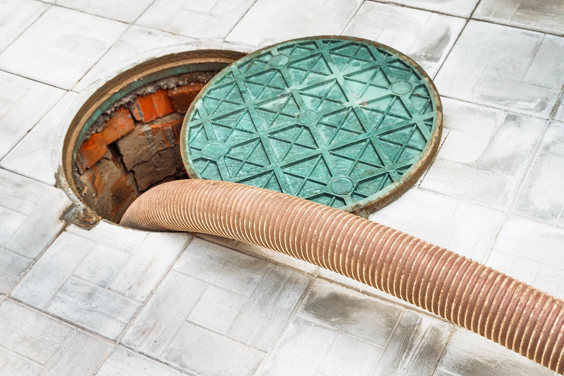 Vacuum hose inserted into an open manhole for cleaning or pumping. Vacuum hose inserted into an open manhole for cleaning or pumping.
